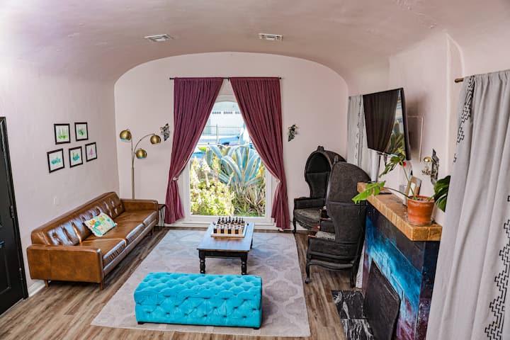Living room with high ceilings, comfortable leather couch, wool rug, beautiful succulent plants and glamorous porter chairs.  