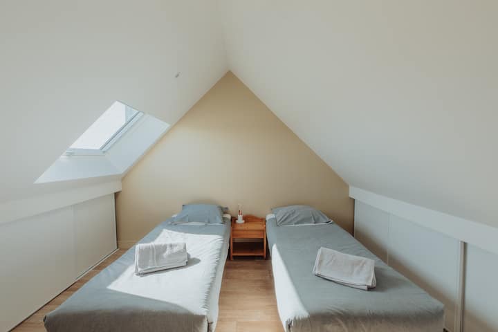 Chambre mansardée avec deux lits simples.