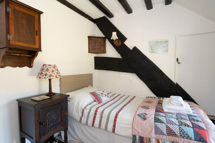 Pretty single room, single bed, chest of drawers, hanging space and mirror. 16th century timbers showing the original roof line. Handmade patchwork quilt by Moyra's talented sister