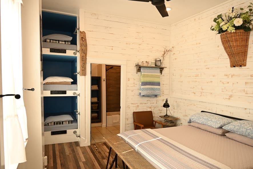 Главна спална соба во Roost Suite, со соседна бања и три двокреветни легла со болнички душеци. Секоја од каблите на спрат има свој електричен штекер.  