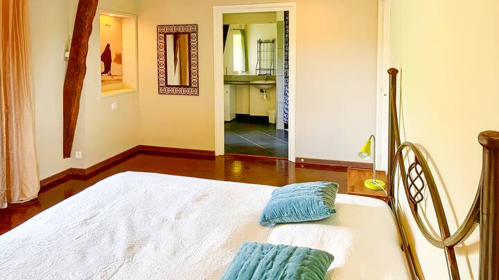 חדר שינה עם מיטת מתכת, גישה לחדר רחצה פרטי עם כיור ומקלחת