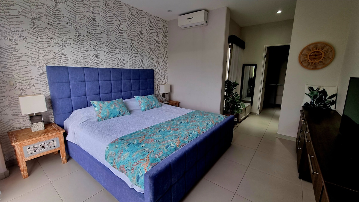 غرفة نوم أنيقة مع سرير بمقاس كينج، مزينة بتفاصيل نابضة بالحياة وأثاث ريفي. مسكن مريح مع مكيف هواء والكثير من الضوء الطبيعي