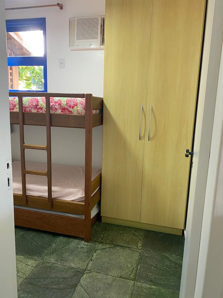 Habitación de la casa ubicada en la planta baja. Tiene ventilador, aire acondicionado, una litera con una cama deslizante y un armario.