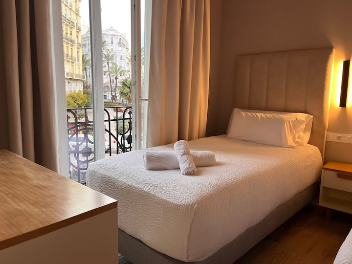Room with two separate beds, table, comfortable, towels and great natural lighting thanks to the windows overlooking the park, creating a bright and cozy environment for a comfortable stay.