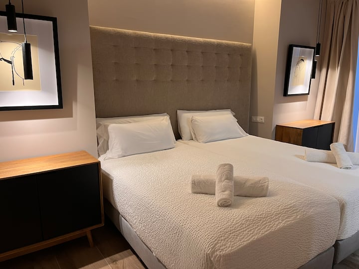 Room with two united beds, towels, dressers and space to put a cot. It has an en-suite bathroom, offering comfort and privacy for a pleasant stay.