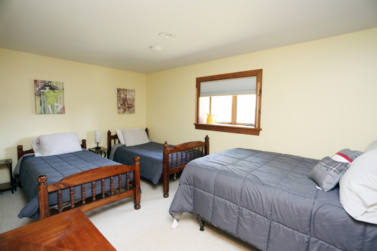 Amplio dormitorio en la planta baja al otro lado del pasillo de un baño completo. Cama tamaño queen y dos camas individuales.