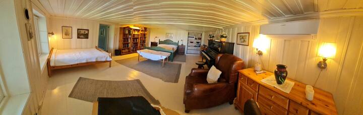 Picha ya Panoramic ya chumba cha kulala kilicho na, kitanda mara mbili (sentimita 150), kitanda kimoja pana (sentimita 120), viti vya mikono, meza ya chini, piano na vitabu vingi (pia vitabu vingi vya watoto) ambavyo vinaweza kusomwa ukiwa hapa. Pia tuna kitanda cha mtoto. Chumba kina pampu ya joto.