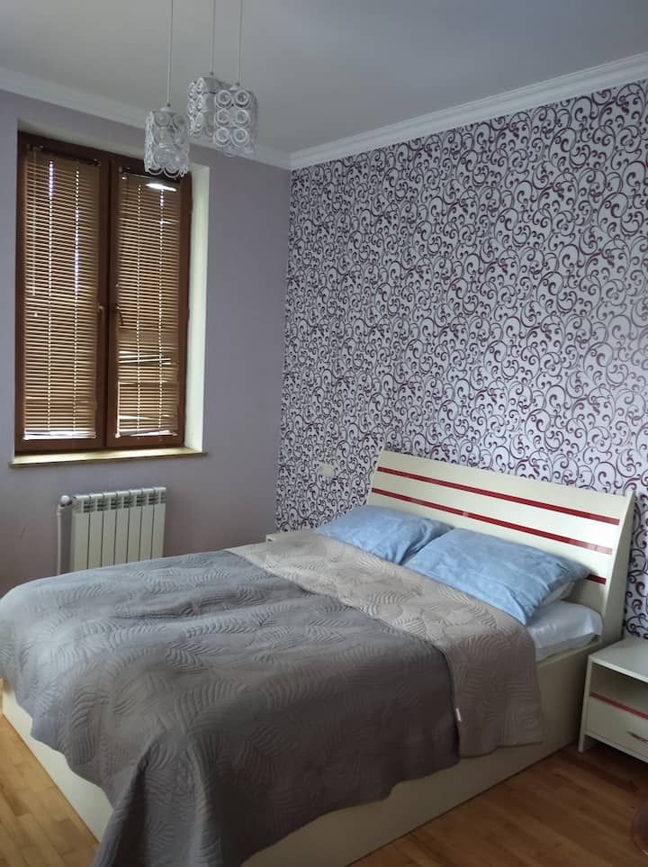 Spálňa s malou manželskou posteľou a otvoreným balkónom