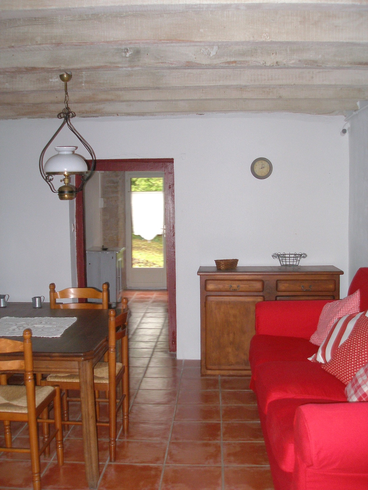 View of the living room with its wide wooden beams and beautiful brightness. The rustic fireplace adds charm to this relaxing space, perfect for winter evenings. Direct access to the outside makes it easy to enjoy the garden.