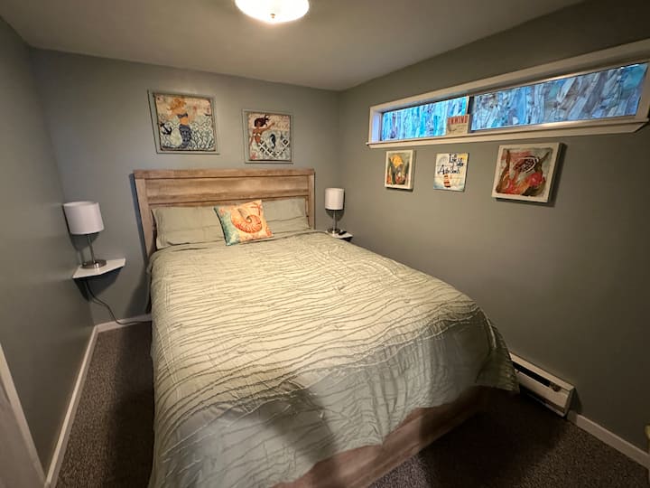 Second bedroom with wall mounted smart TV, closet and dresser. Lamps have a USB port. 