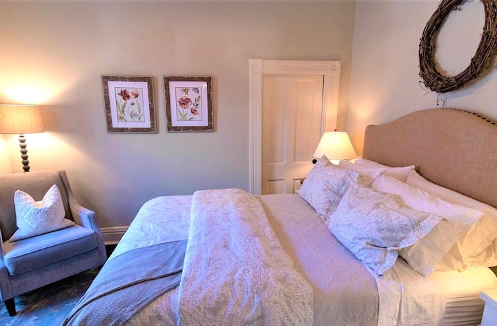 The main downstairs bedroom features a comfortable chair and lamp for reading and is conveniently located next to the full bathroom.