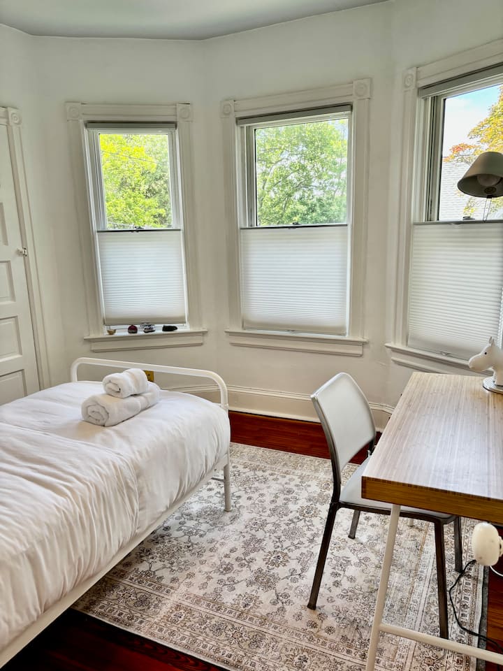 מיטה זוגית עם שולחן כתיבה, שידת לילה ומנורה. 