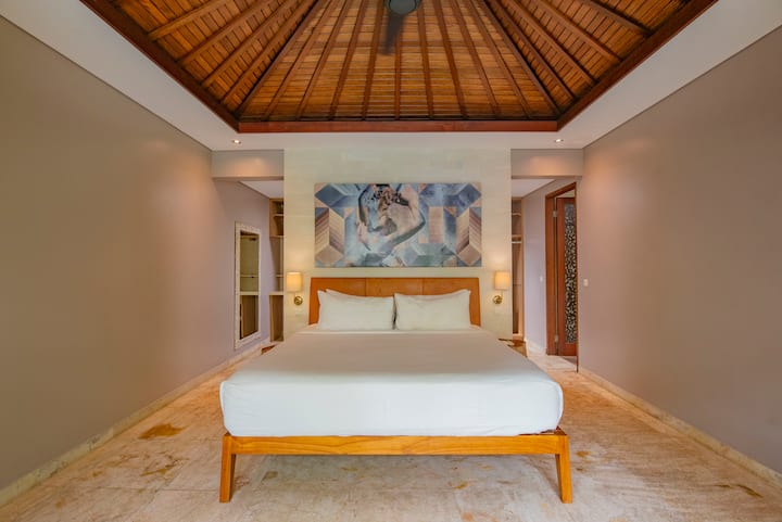 The master bedroom at Kejora 5 features a king bed, a spacious wardrobe, and an ensuite bathroom with a bathtub, along with direct views of the pool and garden.