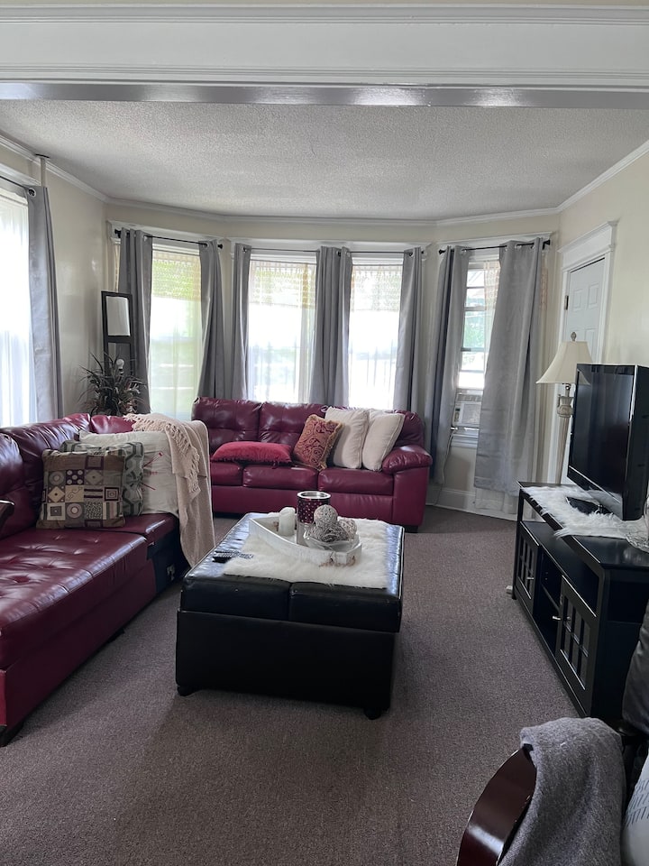 Accogliente soggiorno con abbondante luce naturale proveniente da grandi finestre regolabili con tende oscuranti.  Dispone di due divani in pelle rossa con letto ottomano come pezzo forte, TV da 42" e ampia illuminazione, tra cui lampade da lettura e da ingresso.