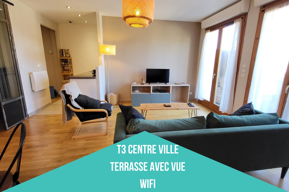 A bright living area is presented, featuring a comfortable seating arrangement that includes a sofa and a lounge chair. A coffee table is centered between the seating and a TV stand. Large windows allow natural light to fill the space, enhancing the welcoming environment.