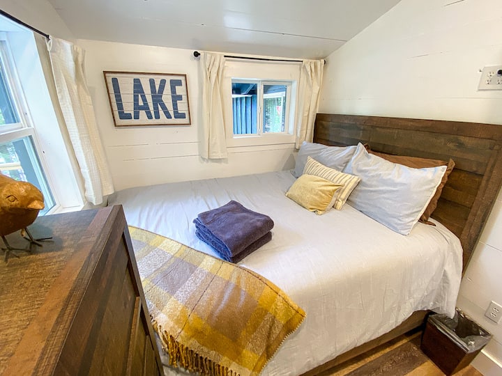 Chumba cha kulala kina kitanda cha malkia na kitanda cha ghorofa mbili, na kifua cha droo kwa ajili ya kuhifadhi nguo.