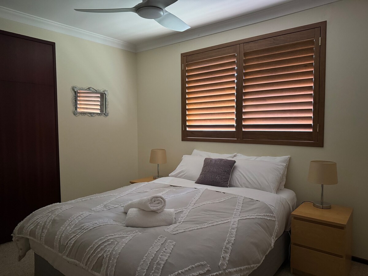 Queen bed with built-in wardrobe and ceiling fan.