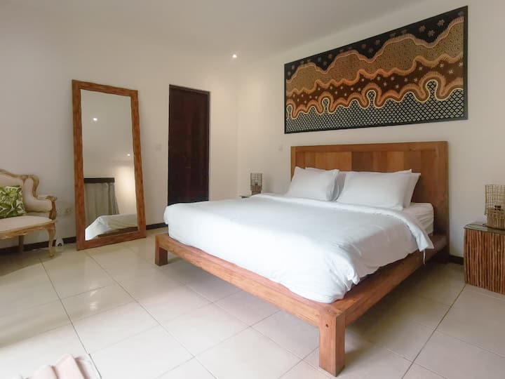 Cozy and bright, this room features a high-quality king-size bed, standing mirror, elegant wooden furniture, tropical garden views, and its own enclosed ensuite bathroom.