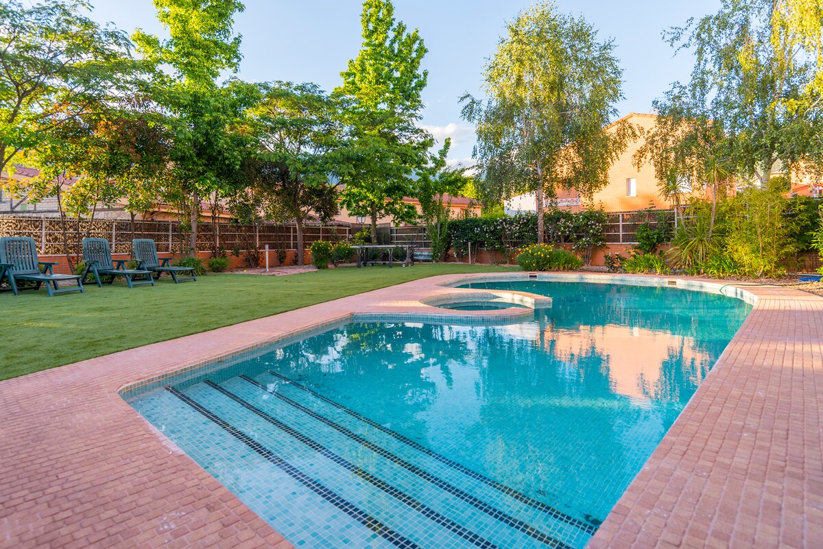 A private salt-water pool is surrounded by lush greenery and well-maintained landscaping. Comfortable lounge chairs are positioned on the grass near the pool, providing a relaxing area for sunbathing. The space is designed for tranquil outdoor enjoyment.