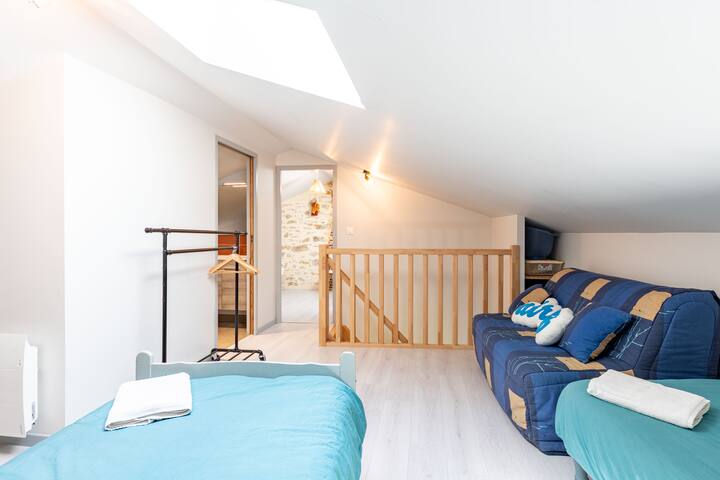 Dorm on the second floor with a sofa, a double bed and 3 single beds (one in a cabin). Bathroom visible on the landing.