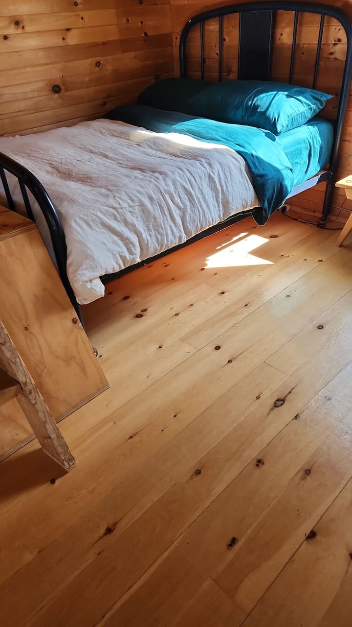 Tweepersoonsbed in open ruimte. Comfortabele kussens in verschillende vormen en een warm dekbed. Zomerdessens in de linnenkast.