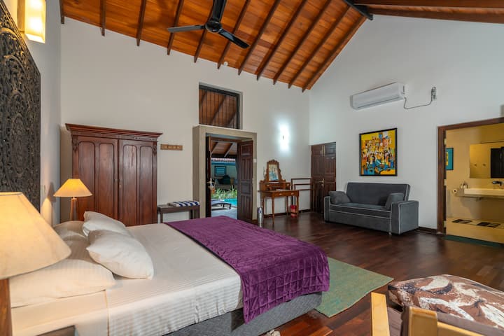 This is a large bedroom (18ft x 20ft) and has an attached toilet with bath and shower. Has wooden parquet flooring and some antique wooden furniture like the cupboard & dressing table.Is air-conditioned and has a ceiling fan and smoke detector. 