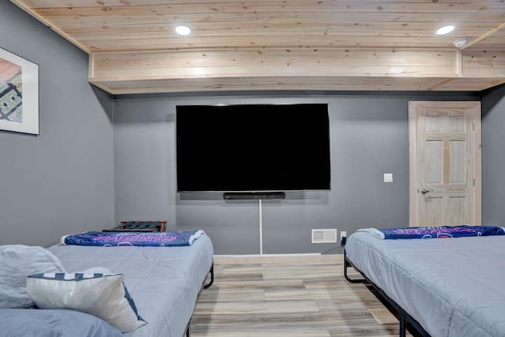 Movie room with 80 inch tv, massage chairs, and two full beds