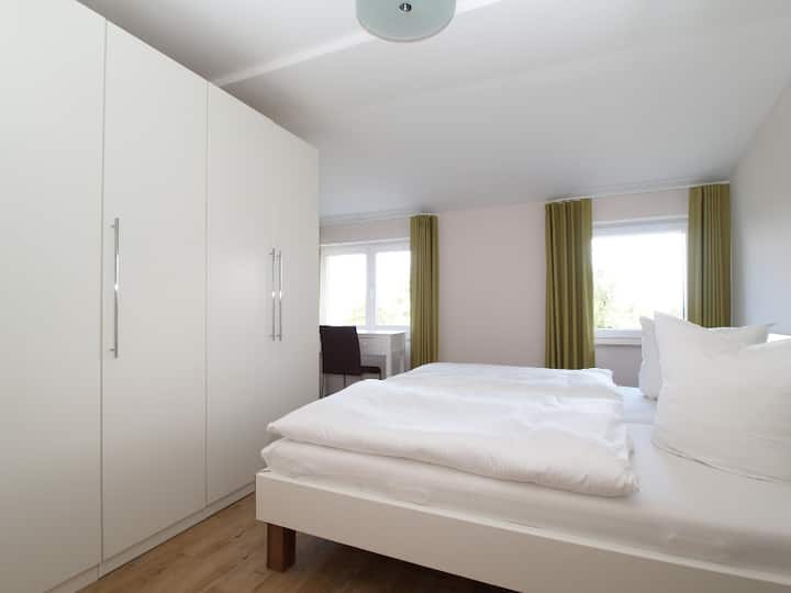 Chambre avec lit double, armoire, console avec chaises et miroir