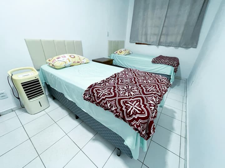 غرفة فردية مع سريرين صندوقيين ومروحة ومرطب هواء ومكواة وطاولة كي الملابس وطاولة/خزانة وشماعات.