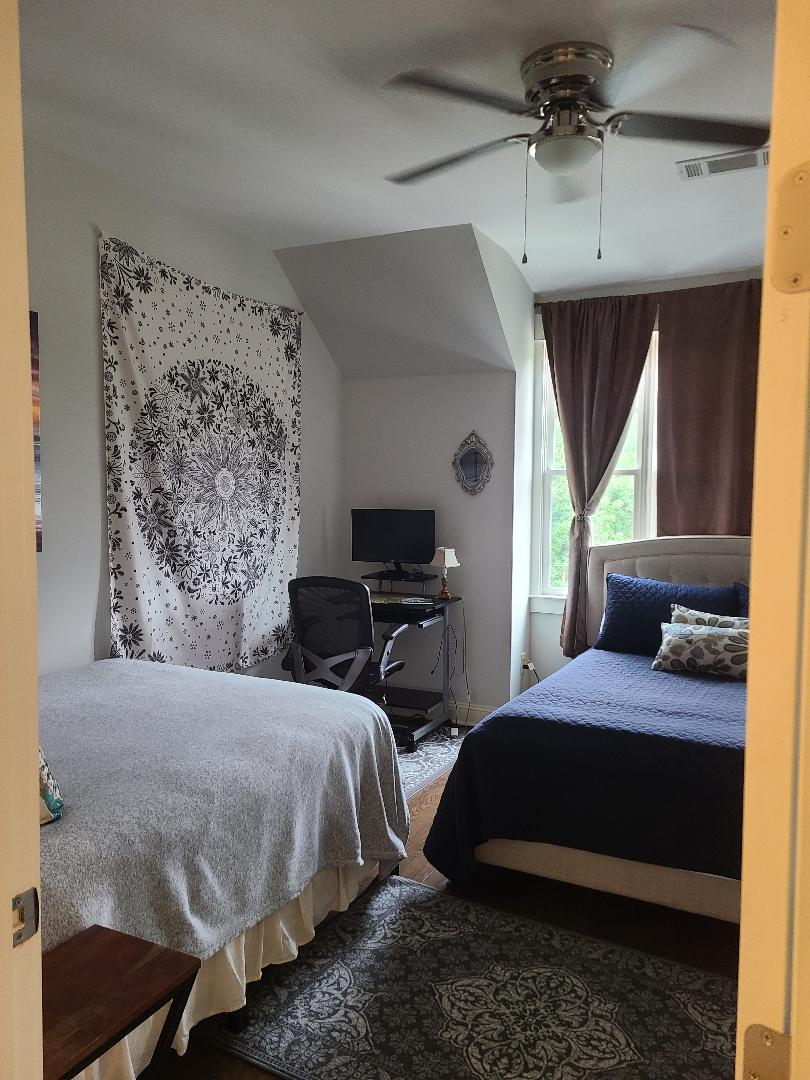 سرير كبير وسرير كامل ومساحة عمل في غرفة النوم.  تلفزيون مثبت على الحائط والنافذة مع إطلالة على مسارات الغابات الوطنية عبر الشارع.