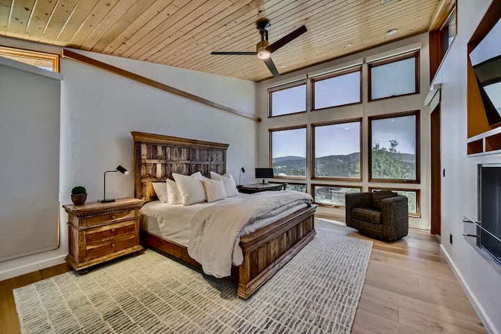 Amplia suite principal con cama tamaño king, techos abovedados y ventanas del piso al techo