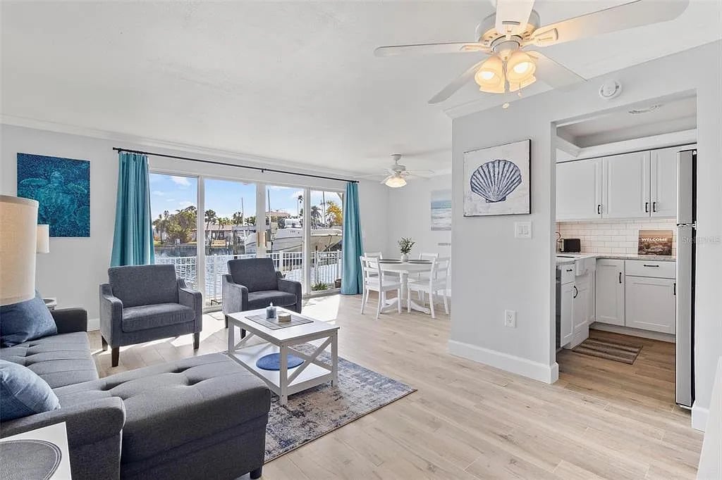 Svetlá, otvorená obývacia izba s pobrežnou výzdobou, stropnými lištami, porcelánovými doskovými podlahami a modernou kuchyňou s pracovnými doskami z recyklovaného skla, raňajkovým barom a úplne novými spotrebičmi z nehrdzavejúcej ocele, ideálna na príležitostnú zábavu.