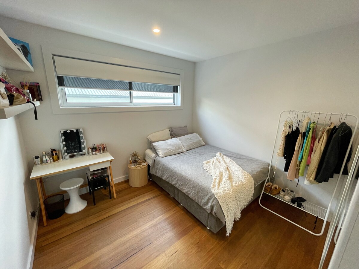 ห้องนอนชั้นล่างมีเตียงขนาดควีนไซส์ที่สะดวกสบาย ม่านบล็อกไลท์ โต๊ะทำงาน และเก้าอี้ มีราวแขวนเสื้อผ้า 