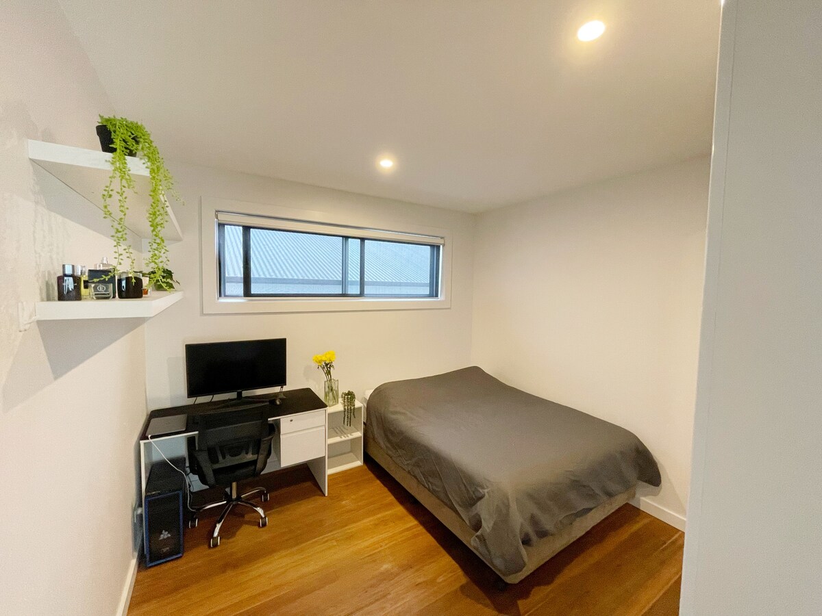 ห้องนอนชั้นล่างมีเตียงขนาดควีนไซส์ที่สะดวกสบาย ม่านบล็อกไลท์ โต๊ะทำงาน และเก้าอี้ มีราวแขวนเสื้อผ้า 