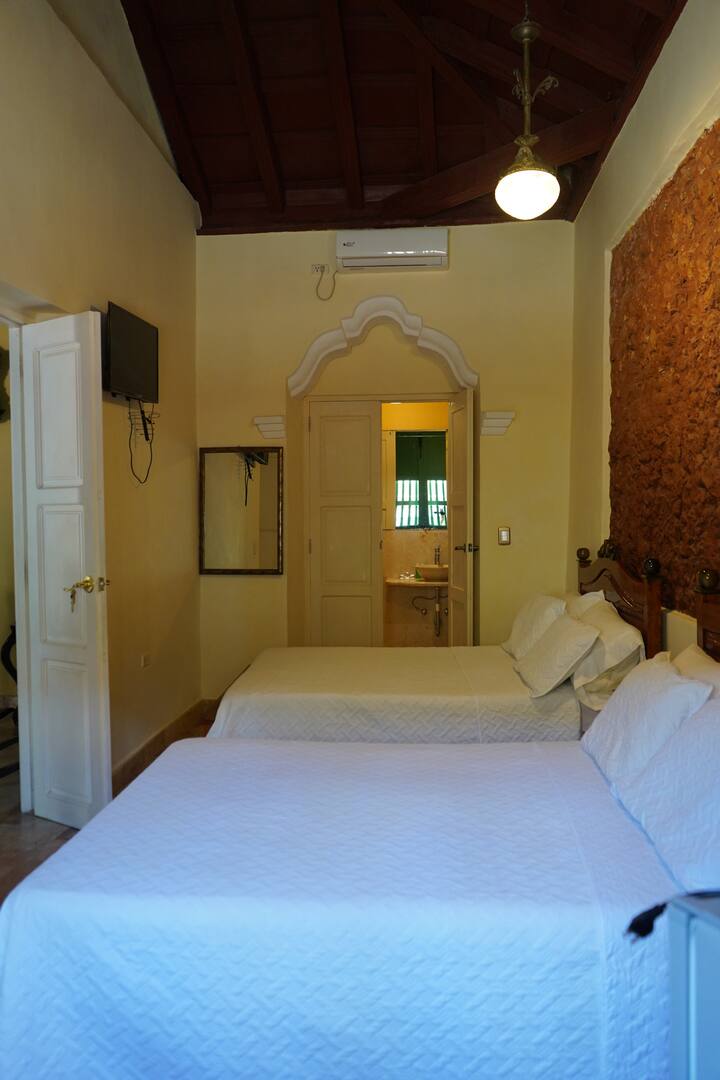 Habitacion con 2 camas dobles , cómodas para descansar después de explorar Trinidad con decoración colonial autentica