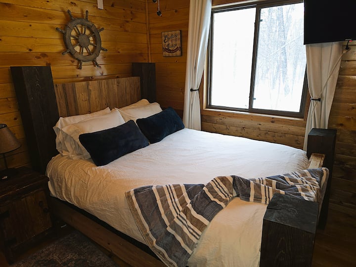 Queen bed in comfortable second bedroom with views of hot tub and forest.