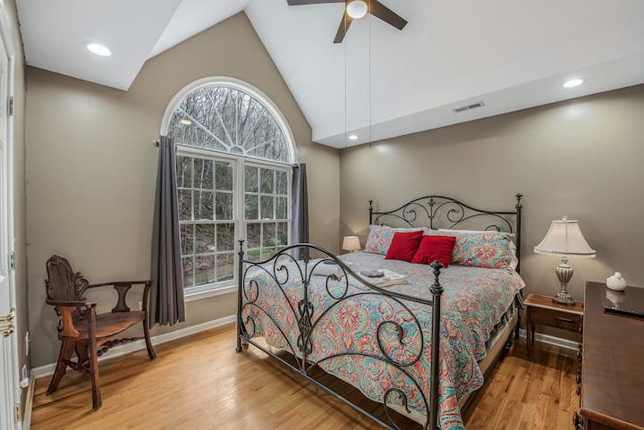 The guest bedroom has a vaulted ceiling, a king bed, and large windows.  Smart TV not shown 