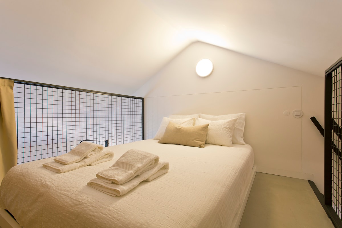 Спална зона с много удобно легло с висококачествено спално бельо и аксесоари. Затъмняващата завеса може да се дръпне, за да се блокира светлината и да се осигури повече уединение.