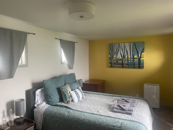 La camera da letto all'alba con una parete gialla e un dipinto. Le lampade sul comodino sono dotate di porte USB. Aria condizionata e due armadietti per i vestiti.