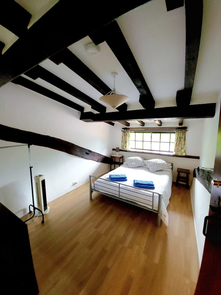 Dormitorio en el primer piso. Incluye ventilador de piso, lámpara, ropa de cama, toallas, cajones, mesita de noche, basurero, taburete y percha portátil para ropa, detector de humo y persianas opacas.