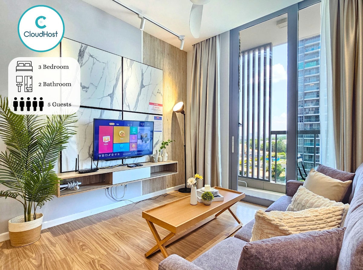 A cozy living area features a comfortable sofa, accompanied by a stylish coffee table. A wall-mounted television displays various channels, while large windows allow natural light to fill the space. The room's neutral tones and contemporary design create a welcoming environment.