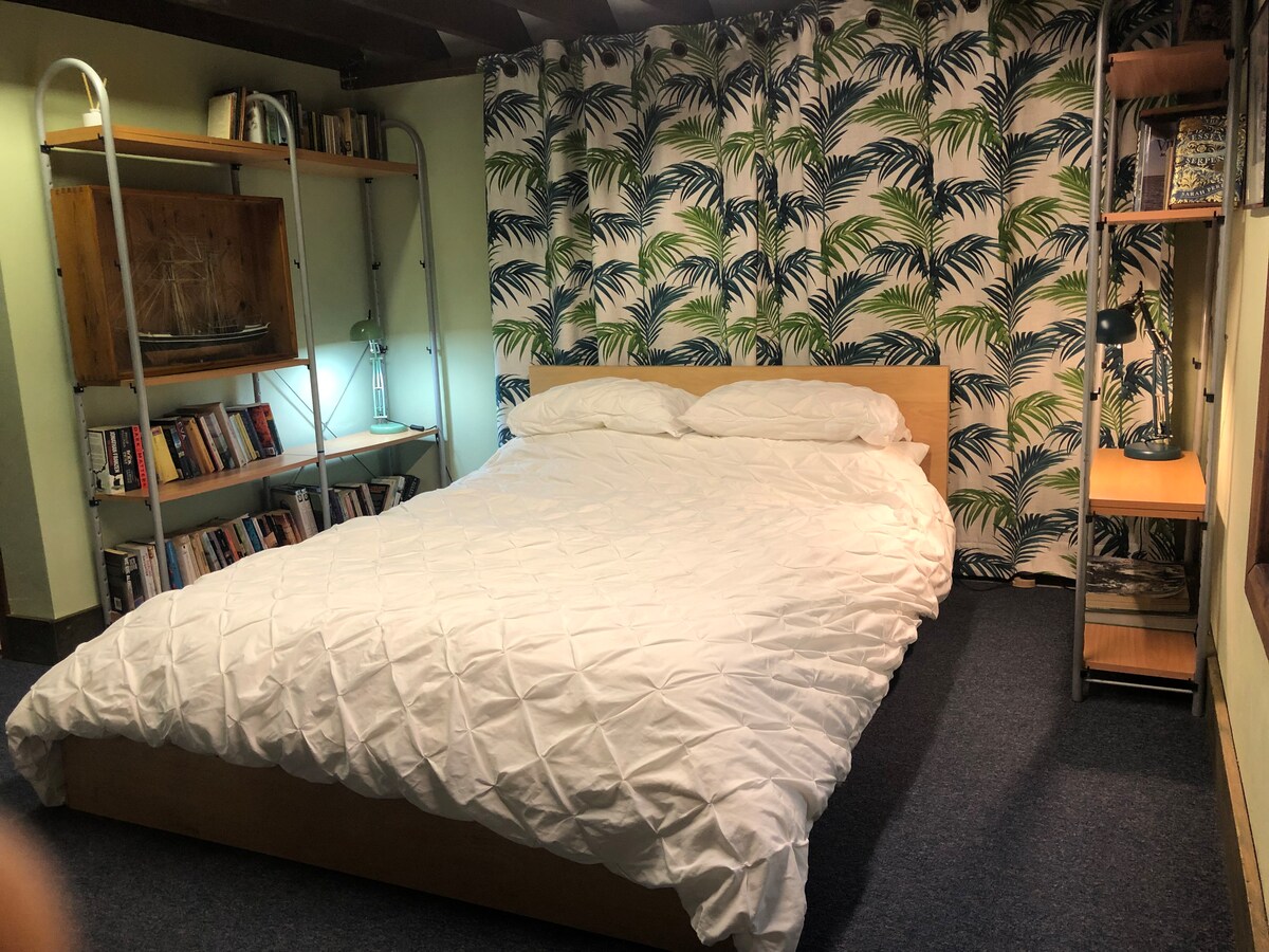 Kitanda cha ukubwa wa malkia kilicho na rafu za vitabu/maktaba ndogo.