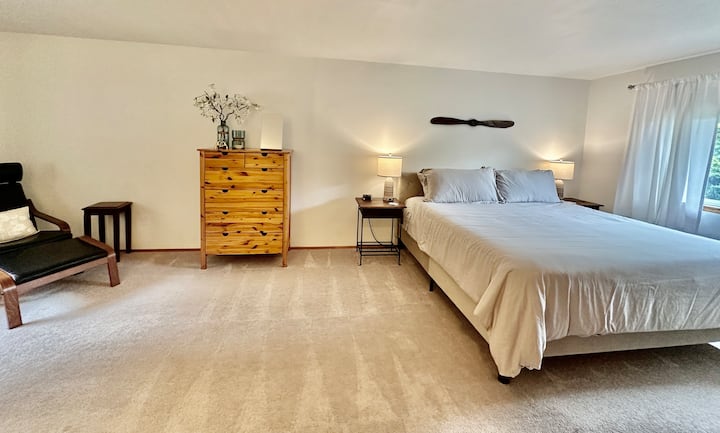 Hlavná spálňa na poschodí s tienidlami na zabránenie prenikania svetla do izby a závesmi filtrujúcimi svetlo.