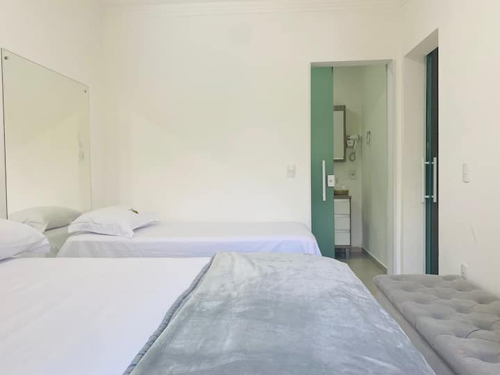 Habitación doble con aire acondicionado, cama individual con canapé, cama adicional y acceso al baño.