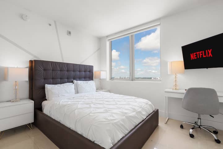 Entra en un dormitorio luminoso con una cómoda cama tamaño queen, una decoración moderna y un televisor de 40 pulgadas, perfecto para relajarse en la intimidad.