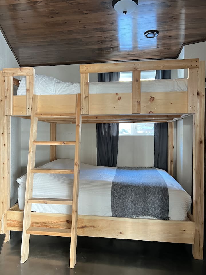 House Bedroom 5: The basement bedroom number 4 has: queen bunk beds, and in the closet: hangers, a mirror, a luggage rack (tv table) and laundry basket. There are also hooks for hanging clothing.