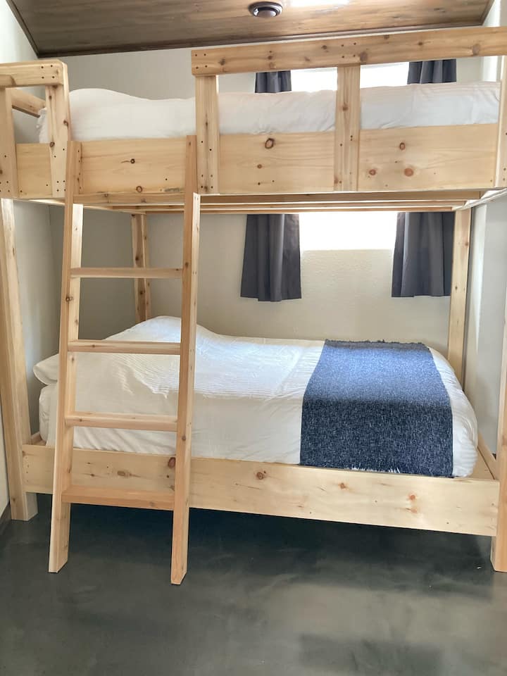 House Bedroom 3: The basement bedroom number 2 has: queen bunk beds, and in the closet: hangers, a mirror, a luggage rack (tv table) and laundry basket. There are also hooks for hanging clothing.