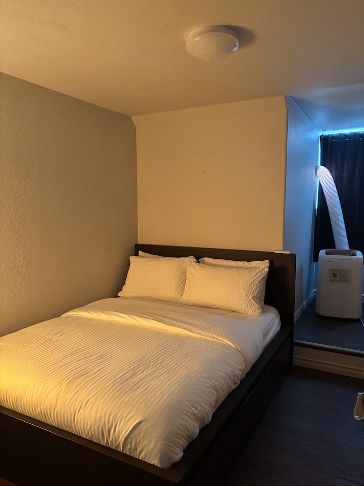 The second bedroom: a queen bed, a mirror, an open cupboard with 3 levels. The bed has two wide drawers.  AC unit can be seen as well.
