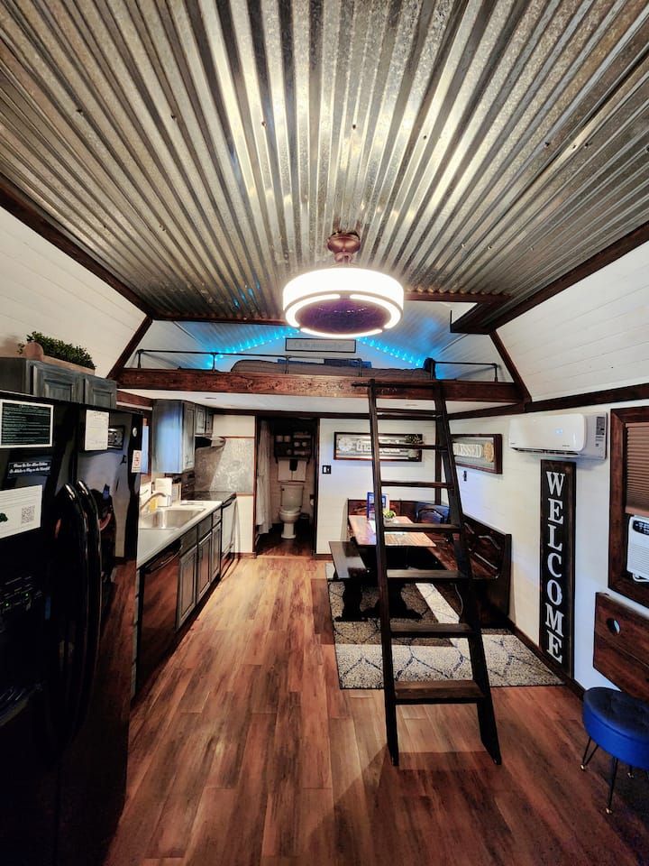 Vue de la cuisine, de la salle à manger et de la 2e zone de couchage située dans un loft confortable avec une entrée en échelle.