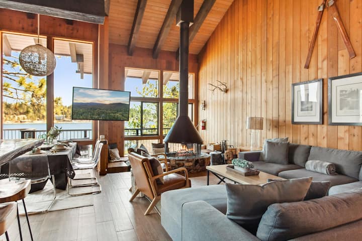 Enjoy a floor-to-ceiling fireplace with panoramic views of the lake, complete with a large couch and sitting area surrounding the fireplace.